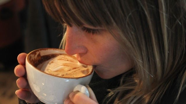 A young woman sips freshly brewed cappuccino.