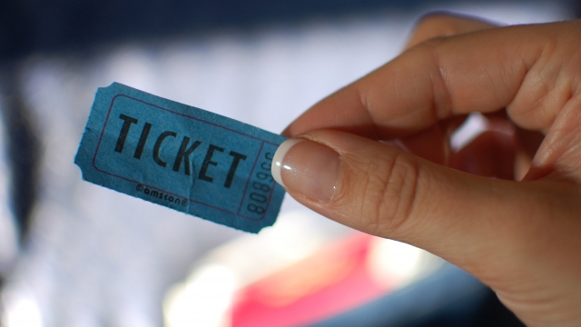 A person holds up a blue admittance ticket.