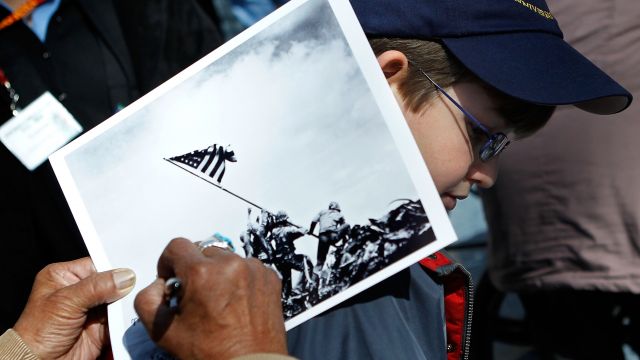 An Iwo Jima veteran signs autograph on the famous WWII photo Raising the Flag on Iwo Jima shot by AP photog Joe Rosenthal.