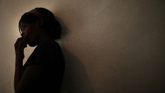 A young sexual assault victim stands in a home with her family.