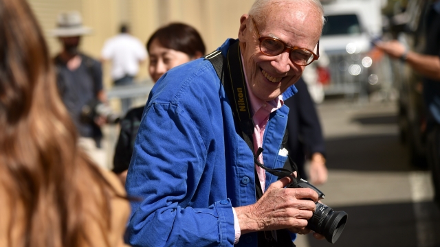 Photographer Bill Cunningham smiling and holding a camera in September 2015