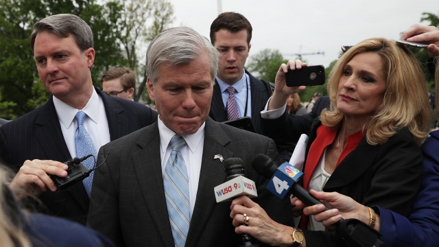 Former Virginia Gov. Bob McDonnell is surrounded by reporters' microphones.