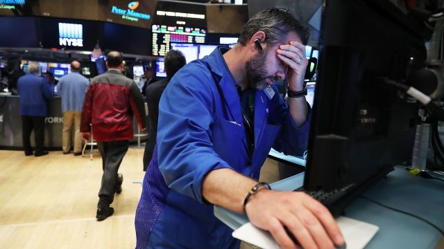 A trader on the floor of the New York Stock Exchange puts his head in his hand.