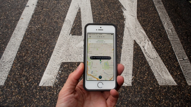Mobile phone using Uber shows how to select a pickup location.