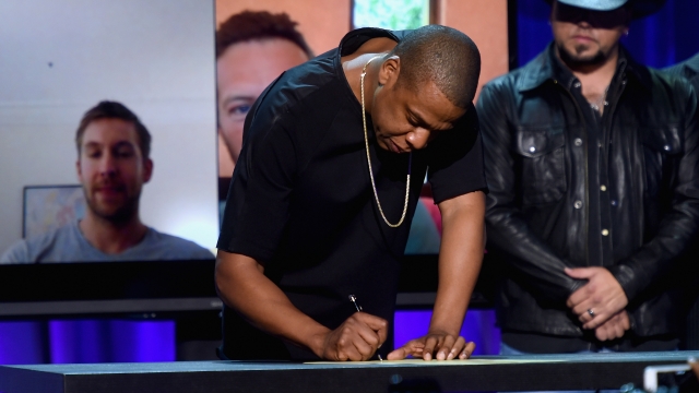 Jay Z signs a paper.