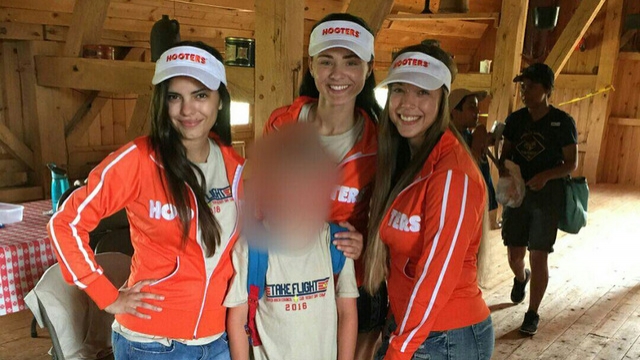 Hooters staffers pose with a Cub Scout during a recent camp.