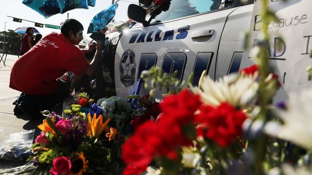 People write condolence notes to the fallen police officers at a growing memorial in front of the Dallas Police Headquarters.