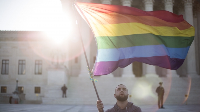 A man waves a LGBTQ rainbow flag outside the U.S. Supreme Court.