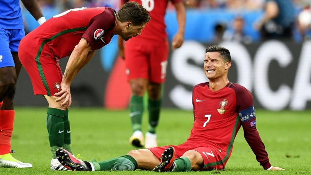 Cristiano Ronaldo of Portugal lies injured as teammate Adrien Silva of Portugal checks on him.