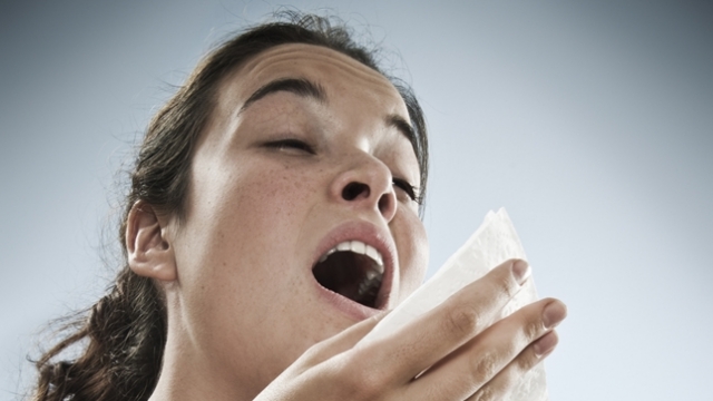 An image of a woman sneezing.