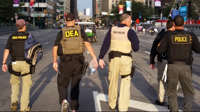 DEA officers walk on a street.