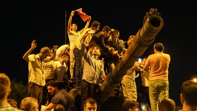 People gather on top of a Turkish army tank.