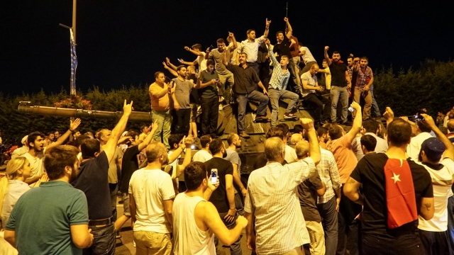 People gather on top of a Turkish army tank at Ataturk Airport