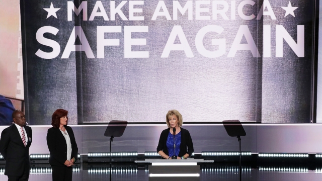 The parents, two women and a man, stand below a sign that says, "Make America safe again."