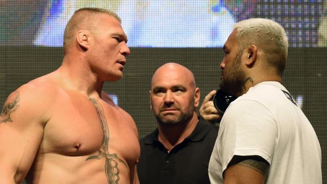 UFC President Dana White (C) looks on as mixed martial artists Brock Lesnar (L) and Mark Hunt (R) face off.