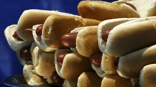 A plate of hot dogs sit on a table.