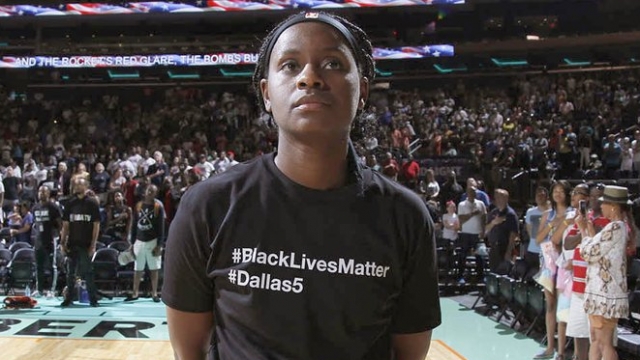 A player for the New York Liberty wears a black T-shirt with #BlackLivesMatter and #Dallas5 while standing before a game.