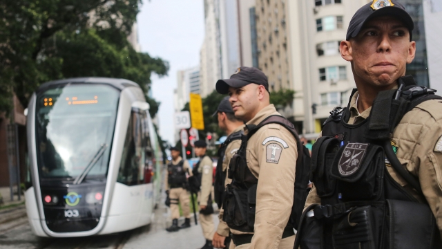 Police watch as a new VLT passes on the day the system was inaugurated ahead of the upcoming Rio 2016 Olympics.