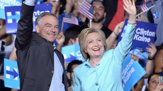 Tim Kaine and Hillary Clinton wave as they stand in front of a crowd during their first official campaign event as a ticket.