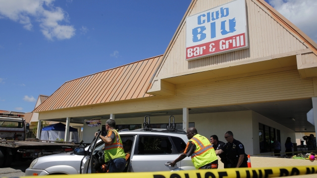 Police remove a car hit by gunfire outside of Club Blu where two people were killed and at least 15 wounded on July 25, 2016