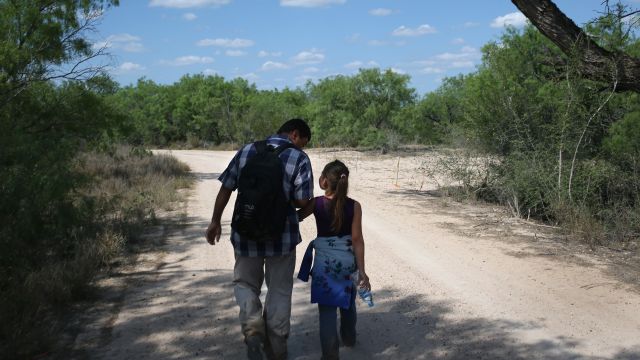 Ania, 9, from El Salvador walks with her father through the South Texas countryside after crossing the Rio Grande.