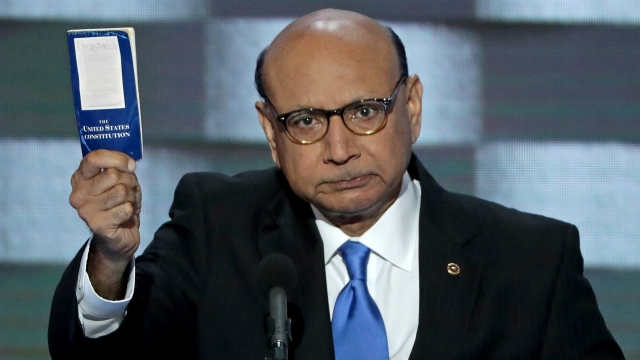 Khizr Khan holds up a blue pocket-size copy of the U.S. Constitution.