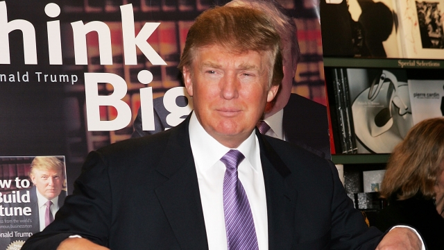 Donald Trump gestures as he poses for a photo during an in-store appearance to sign copies of 'How To Build Wealth.'