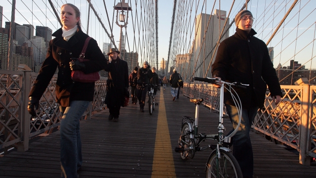 Commuters walk across the Brooklyn Bridge in the evening.
