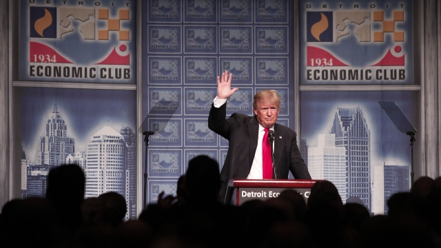 Donald Trump stands at a podium and speaks to a crowd.