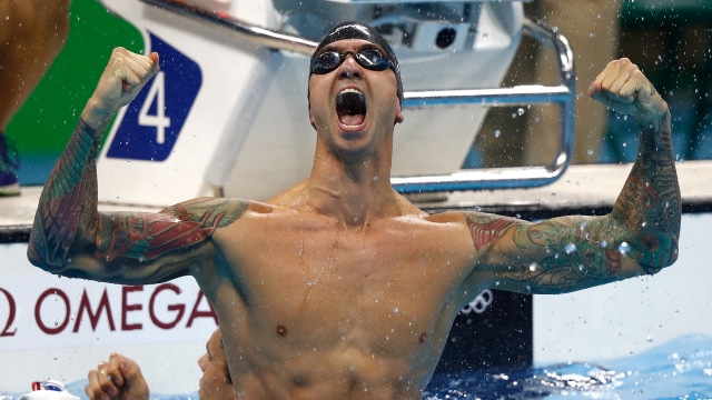 Anthony Ervin holds his fists up in the air with muscles flexed celebrating his Olympic gold medal swimming win.