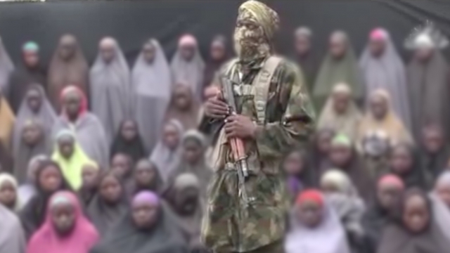 Missing Chibok girls sit behind a Boko Haram fighter