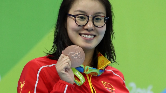 Olympic swimmer Fu Yuanhui holds up her medal.