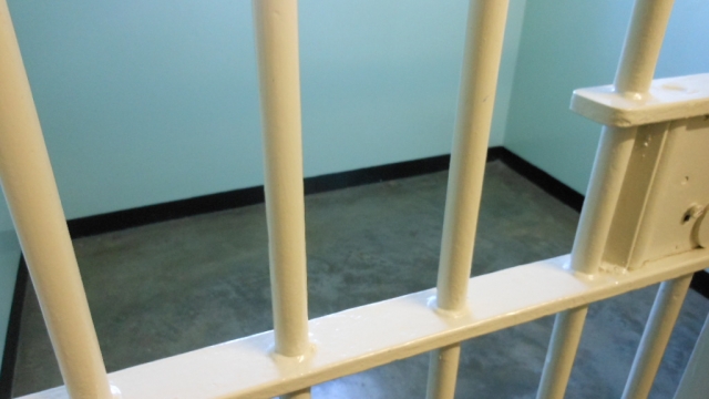 Cream color jail bars with a cell with a light blue wall in the background.