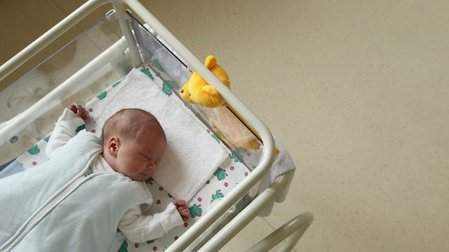 A newborn baby lies in the maternity ward of a hospital.