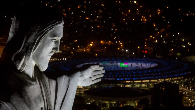 The Christ the Redeemer statue is seen at sunset in front of the Maracana Stadium.