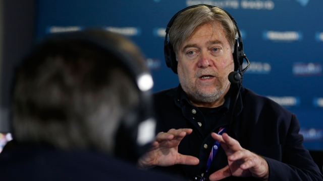Stephen K. Bannon wears a headset and holds his hands up as he's talking. He wears a navy button-down shirt. He has gray hair
