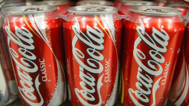Coca-Cola cans sit on a shelf