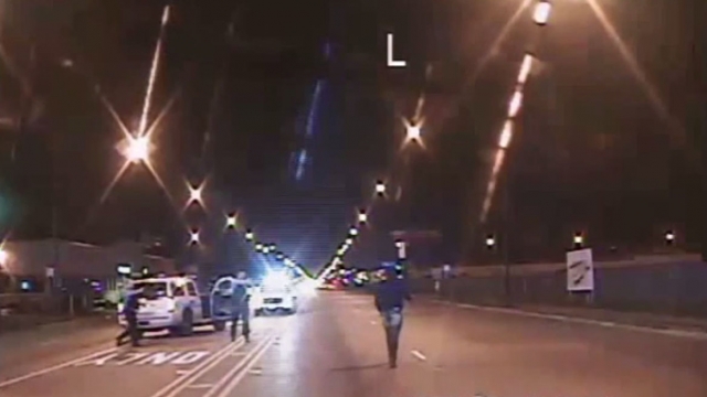 A still image from dash cam video shows Laquan McDonald walking down the middle of a street as two officers point their guns.