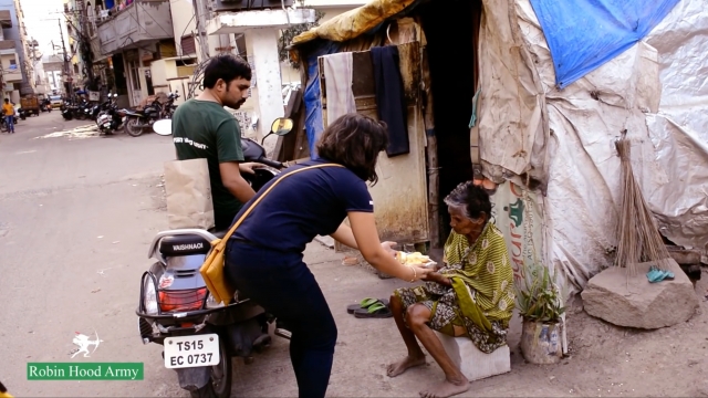 A volunteer with the Robin Hood Army gives food to an elderly hungry woman in India.