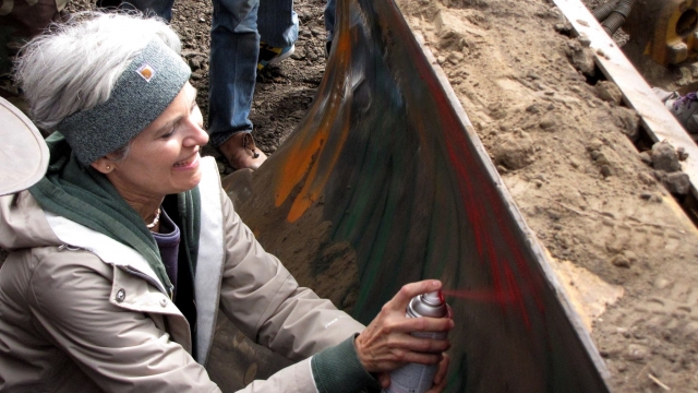 Green Party presidential candidate Dr. Jill Stein spray paints a bulldozer as part of a Dakota Access Pipeline protest.