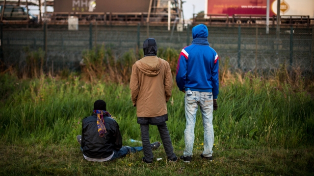 Men watch as a train arrives at the Eurotunnel terminal in Coquelles on July 31, 2015 in Calais, France.