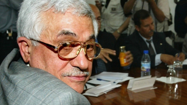 Palestine's President Mahmoud Abbas in the foreground at a conference table with others in the background