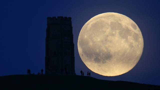 The moon rises over people gathered on Glastonbury Tor on July 31, 2015 in Somerset, England.