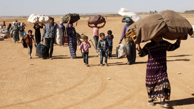 Newly arrived Syrian Kurdish refugees walk with their belongings after crossing into Turkey.