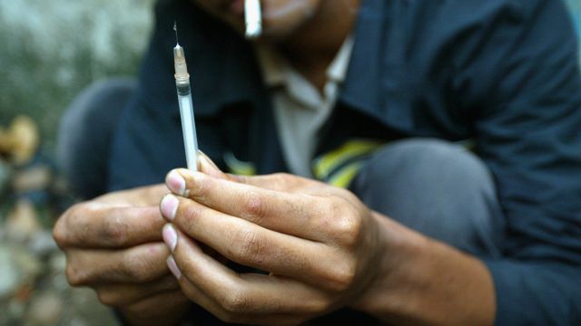 A drug addict prepares a needle.