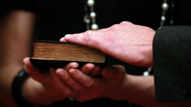 Two people hold a Bible.