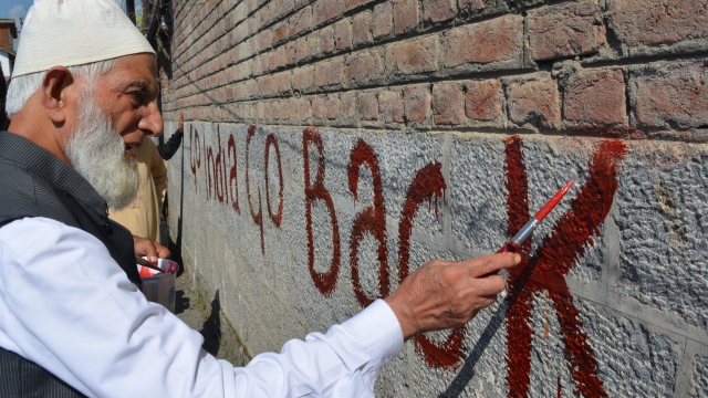 A protester paints a wall in Kashmir.