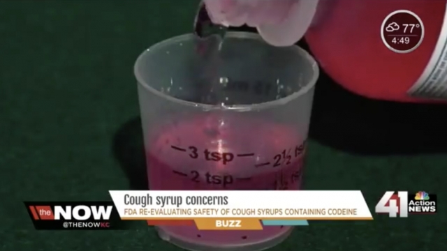 Cough syrup is poured into a measuring cup.