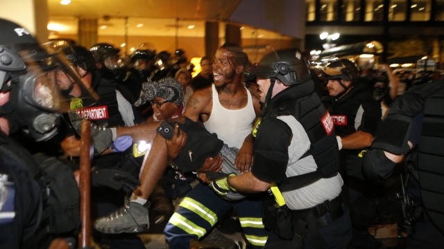 Police and protesters carry someone injured during the violent protests in Charlotte.