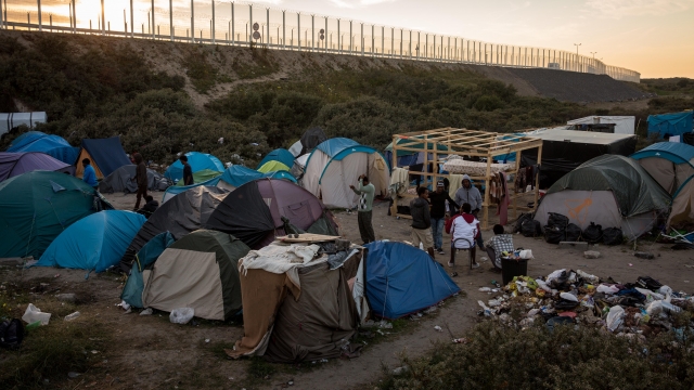 The sun sets behind a makeshift camp near the port of Calais, France.